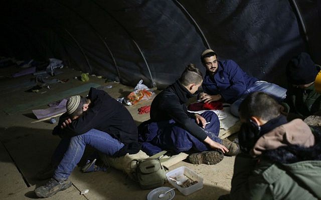 Israeli youth sit in a tent in the outpost of Amona in the West Bank, on December 17, 2016. (Miriam Alster/Flash90)