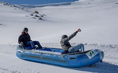 Israelis use a rubber dinghy to slide down a slope at the Mount Hermon ski resort on December 20, 2016. (Basel Awidat/Flash90)