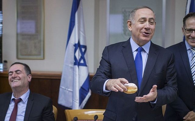 Prime minister Benjamin Netanyahu holds a traditional Hanukkah doughnut before the start of the weekly cabinet meeting at the Prime Minister office in Jerusalem on December 25, 2016. (Yonatan Sindel/Flash90) Prime minister Benjamin Netanyahu holds a traditional Hanukkah doughnut before the start of the weekly cabinet meeting at the Prime Minister office in Jerusalem on December 25, 2016. (Yonatan Sindel/Flash90)
