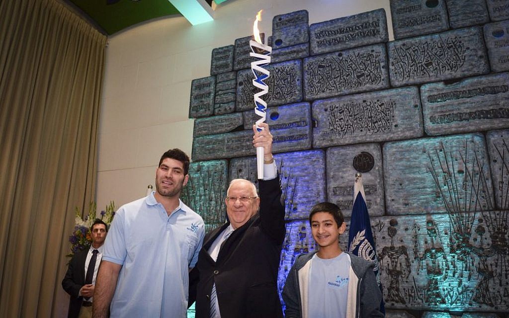Judoka and Olympic medalist Ori Sasson (L) passes the Maccabiah torch to President Reuven Rivlin (C) during the 20th Maccabiah Torch Race event at the President's Residence in Jerusalem on December 26, 2016. (Photo by Haim Zach/GPO)