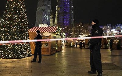 Firefighters look at a toppled Christmas tree after a truck ran into a crowded Christmas market and killed several people in Berlin, Germany, Monday, Dec. 19, 2016. (AP Photo/Michael Sohn)