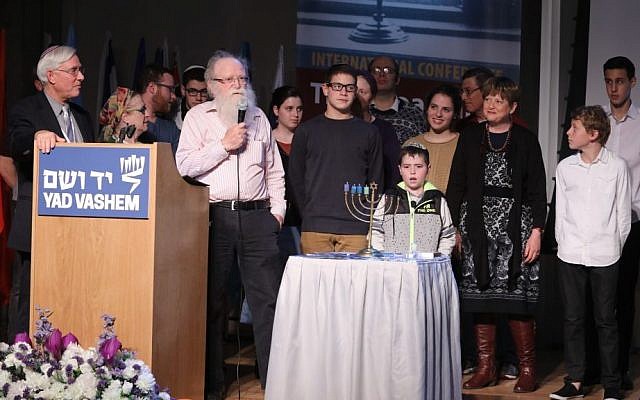 Ephraim Kaye, Yad Vashem International School for Holocaust Studies, watches as Yehuda Mansbach and family light his grandfather's menorah, December 2016. (Yad Vashem/Isaac Harari)