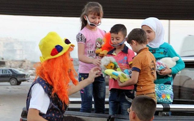 This undated photo shows Syrian social worker Anas al-Basha, 24, dressed as a clown, distributing toys to children in Aleppo, Syria. (Courtesy of Ahmad al-Khatib, via AP) 