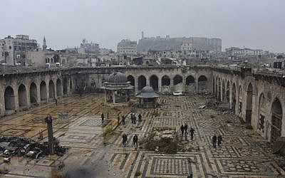 This photo released by the Syrian official news agency SANA, shows Syrian troops and pro-government gunmen marching walk inside the destroyed Grand Umayyad mosque in the old city of Aleppo, Syria, Tuesday, Dec. 13, 2016. (SANA via AP) 