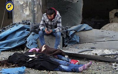 A Syrian boy sitting next to bodies after artillery fire struck the Jub al-Quba district in Aleppo, Syria, November 30, 2016. (Syrian Civil Defense White Helmets via AP).