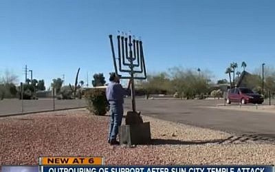 A man works to fix the menorah outside Temple Beth Shalom in Sun City, Arizona, that was damaged in suspected hate crime on December 25, 2016. (screen capture: ABC 15 Arizona)