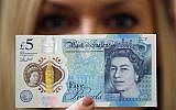 A Bank of England employee shows the new five pound note at the Bank of England Museum in London on Sept. 6, 2016.  (AP Photo/Frank Augstein, File)