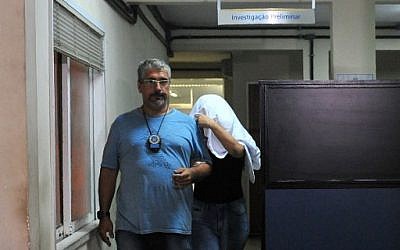 A Brazilian civil policeman escorts the wife of Greece's ambassador to Brazil Kyriakos Amiridis, Francoise de Souza Oliveira, who murdered him in a plot hatched with her police officer lover, who confessed to the crime, on December 30, 2016 in Rio de Janeiro. (AFP/Fabio Teixeira)