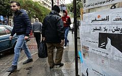 People walk past a newspaper stand displaying the As-Safir newspaper in Beirut's Hamra neighborhood on December 31, 2016. (Anwar Amro/AFP)