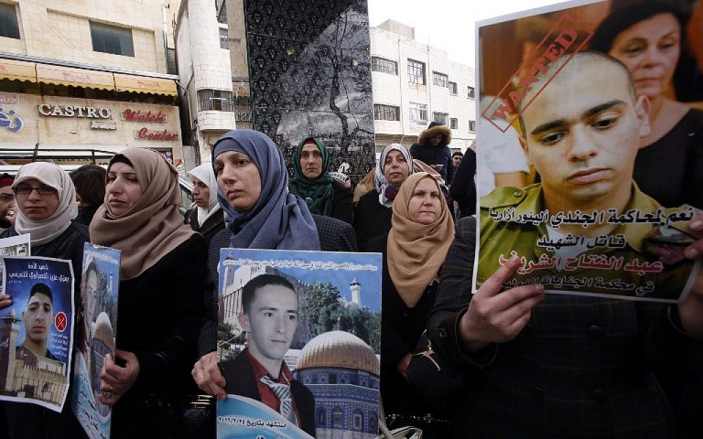Rajaa (C), holds a poster of her son Abdul Fatah al-Sharif as Palestinians gather in the street in the West Bank town of Hebron on January 4, 2017, during the trial of Israeli soldier Elor Azaria (portrait-C) who killed Sharif, a wounded Palestinian stabber as he lay on the ground,
(AFP PHOTO / HAZEM BADER)