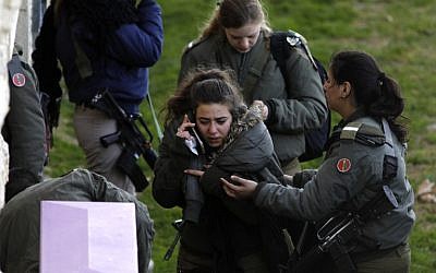 An Israeli soldier comforts a comrade near the site of a vehicle-ramming terror attack in Jerusalem, in which four soldiers were killed and 16 injured on January 8, 2017. (AFP PHOTO / MENAHEM KAHANA)