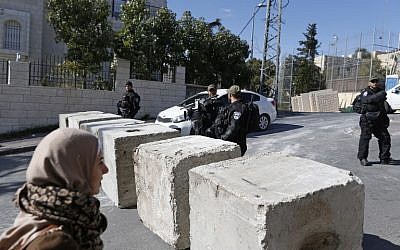 Israeli security forces stand next to newly-installed concrete blocks in the East Jerusalem neighborhood of Jabel Mukaber on December 9, 2017. (AFP/AHMAD GHARABLI)