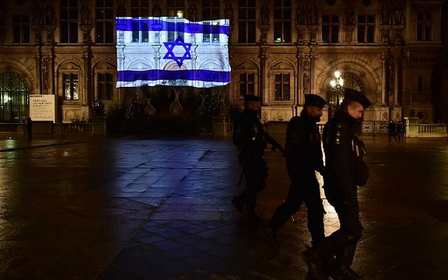 French CRS anti-riot police officers patrol as the Israeli flag is projected onto the facade of the Hotel de Ville in Paris on the night of January 10, 2017, in tribute to the victims of an attack in Jerusalem on January 8.( AFP PHOTO / CHRISTOPHE ARCHAMBAULT)