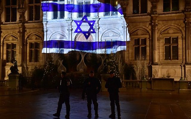 French CRS anti-riot police officers patrol as the Israeli flag is projected onto the facade of the Hotel de Ville in Paris on the night of January 10, 2017, in tribute to the victims of an attack in Jerusalem on January 8.(AFP PHOTO / CHRISTOPHE ARCHAMBAULT)