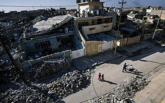 Iraqis children walk between ruined buildings in Mosul's Qadisiyah neighbourhood on January 11, 2017, during an ongoing military operation against the Islamic State (IS) group. (AFP/Dimitar DILKOFF)