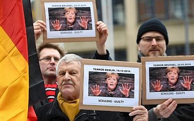 Demonstrators hold placards protesting German Chancellor Angela Merkel in front of the venue where Merkel was set to arrive at in Brussels on January 12, 2017. (AFP Photo/Emmanuel Dunand)