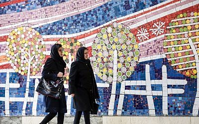 Two Iranian women walk along a street past a mosaic mural on the first anniversary of the nuclear agreement, in the capital Tehran on January 14, 2017. (AFP/ATTA KENARE)