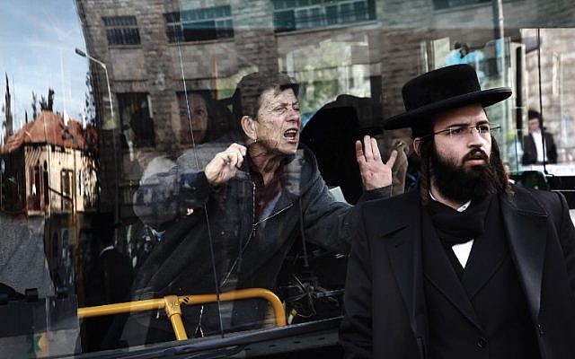 A woman on a bus reacts as ultra-Orthodox Jews block a bus during a protest against ultra-Orthodox service in the IDF, in the neighbourhood of Mea Shearim, Jerusalem, January 17, 2017. (AFP/MENAHEM KAHANA)
