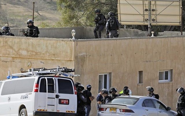 Israeli policemen take position next to a building in the unrecognized Bedouin village of Umm al-Hiran in the Negev desert on January 18, 2017. (AFP Photo/Menahem Kahana)