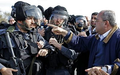 Joint (Arab) List MK Ahmad Tibi, right, confronts an Israeli policeman in a tense standoff with Bedouin protesters in the unrecognized village of Umm al-Hiran in the Negev desert, on January 18, 2017. (AFP Photo/Ahmad Gharabli)