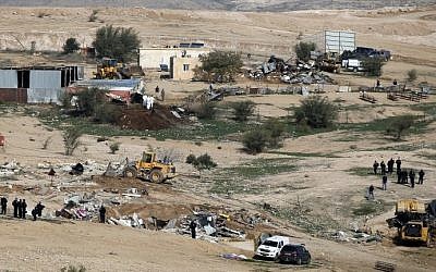 Israeli policemen stand guard as bulldozers demolish homes in the unrecognized Bedouin village of Umm al-Hiran in the Negev desert, on January 18, 2017. (AFP Photo/Menahem Kahana)