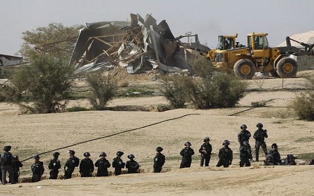 Israeli policemen stand guard as bulldozers demolish homes in the unrecognized Bedouin village of Umm al-Hiran in the Negev desert, on January 18, 2017. (AFP Photo/Menahem Kahana) Israeli policemen stand guard as bulldozers demolish homes in the unrecognized Bedouin village of Umm al-Hiran in the Negev desert, on January 18, 2017. (AFP Photo/Menahem Kahana)