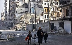 Syrians walk along a damaged street in Aleppo's Tareeq al-Bab neighbourhood on January 18, 2017, a month after government forces retook the northern Syrian city from rebel fighters. (AFP Photo/George Ourfalian)