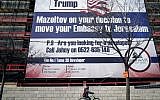 An Israeli child cycles past a giant banner bearing a message of congratulations ('Mazel tov') for incoming US President Donald Trump, covering a building under construction in central Jerusalem on January 20, 2017.  (AFP Photo/Thomas Coex)