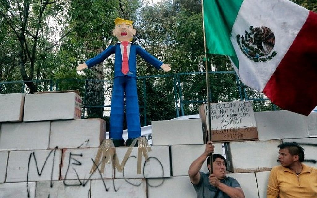 People protest against US President Donald Trump's inauguration next to a fake wall with a Mexican national flag and a dummy representing him in Mexico City on January 20, 2017. (AFP PHOTO / PEDRO PARDO)