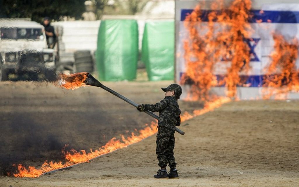 A Palestinian boy sets fire to a line of flames leading to an Israeli flag during a graduation ceremony for Hamas security forces in Gaza City on January 22, 2017. (AFP /MAHMUD HAMS)