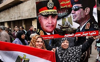 Egyptian women hold their national flag and a poster bearing portraits of President Abdel Fattah al-Sissi and Defense Minister Sedki Sobhi, as they celebrate the sixth anniversary of the 2011 uprising that overthrew former Egyptian president Hosni Mubarak in Cairo's Tahrir Square on January 25, 2017. AFP/STRINGER)