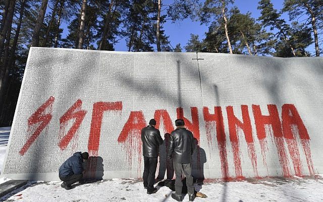 Employees examine Nazi SS graffiti written on a wall dedicated to Polish officers at the Bykovnia Memorial Cemetery, near to Kiev, on January 26, 2017. (AFP PHOTO / Sergei SUPINSKY)