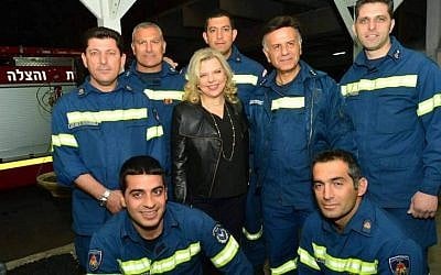 A Cypriot firefighter, standing to the right of Prime Minister Benjamin Netanyahu's wife Sara, is wearing a chief inspector's jacket with three stars, when his rank is apparently only inspector. (Cobi Gidon / GPO)