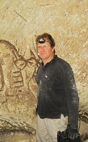 Spelunker Ido Meroz near the engravings he and his colleagues found in a cistern in the Judean lowlands in December 2016. (Mickey Barkal via Israel Antiquities Authority)