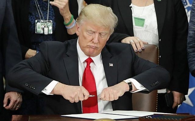 President Donald Trump takes the cap off a pen before signing executive order for immigration actions to build border wall during a visit to the Homeland Security Department in Washington, Wednesday, Jan. 25, 2017. (AP/Pablo Martinez Monsivais)