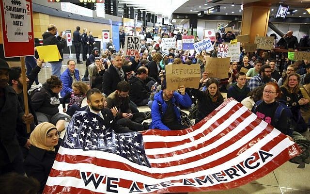 Demonstrators sit down in the concourse and hold a sign that reads "We are America," as more than 1,000 people gather at Seattle-Tacoma International Airport, to protest President Donald Trump's order that restricts immigration to the US, Saturday, January 28, 2017, in Seattle. (Genna Martin/seattlepi.com via AP) Demonstrators sit down in the concourse and hold a sign that reads "We are America," as more than 1,000 people gather at Seattle-Tacoma International Airport, to protest President Donald Trump's order that restricts immigration to the US, Saturday, January 28, 2017, in Seattle. (Genna Martin/seattlepi.com via AP)