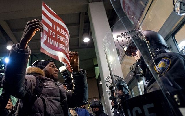 A protester stands facing police officers at an entrance of Terminal 4 at John F. Kennedy International Airport in New York, January 28, 2017 (AP/Craig Ruttle)
