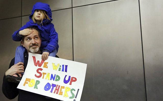 Matt Sernett holds his daughter Wade, 5, atop his shoulders, as more than 1,000 people gather at Seattle-Tacoma International Airport, to protest President Donald Trump's order that restricts immigration to the US, Saturday, Jan. 28, 2017, in Seattle. (Genna Martin/seattlepi.com via AP) 
