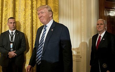 President Donald Trump, center, accompanied by Vice President Mike Pence, right, arrives for a White House senior staff swearing in ceremony in the East Room of the White House, Sunday, Jan. 22, 2017, in Washington. (AP Photo/Andrew Harnik)