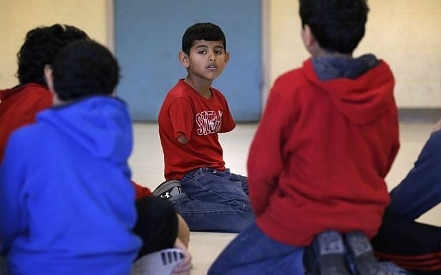 In this Dec. 10, 2016 photo, Syrian refugee Ahmad Alkhalaf kneels with friends after praying during a day camp for local Muslim children in Sharon, Mass. (AP Photo/Charles Krupa)