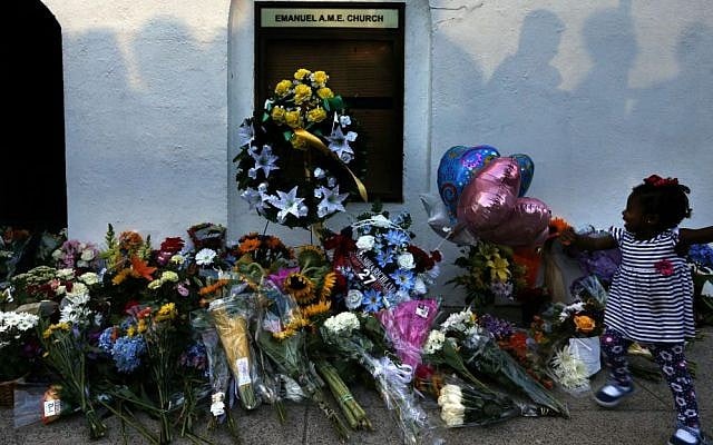 In this Thursday, June 18, 2015 file photo, mourners pass by a make-shift memorial on the sidewalk in front of the Emanuel AME Church following a shooting by white supremacist Dylann Roof in Charleston, South Carolina. (AP Photo/Stephen B. Morton, File)