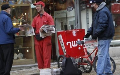 A man passes out the free newspaper Israel Hayom to passersby on Ben Yehuda Street in Jerusalem, January 4, 2011. (Miriam Alster/Flash90)