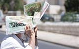 A man carries a newspaper over his head to protect himself from the sun, on a warm summer day in Jerusalem. May 22, 2016. (Zack Wajsgras/FLASH90)