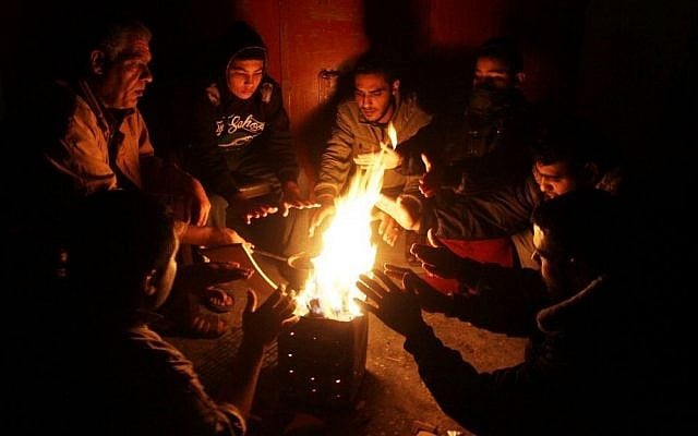 Palestinians warm themselves around a fire during a winter storm, in Rafah, Gaza Strip, on December 1, 2016. (Abed Rahim Khatib/Flash90)