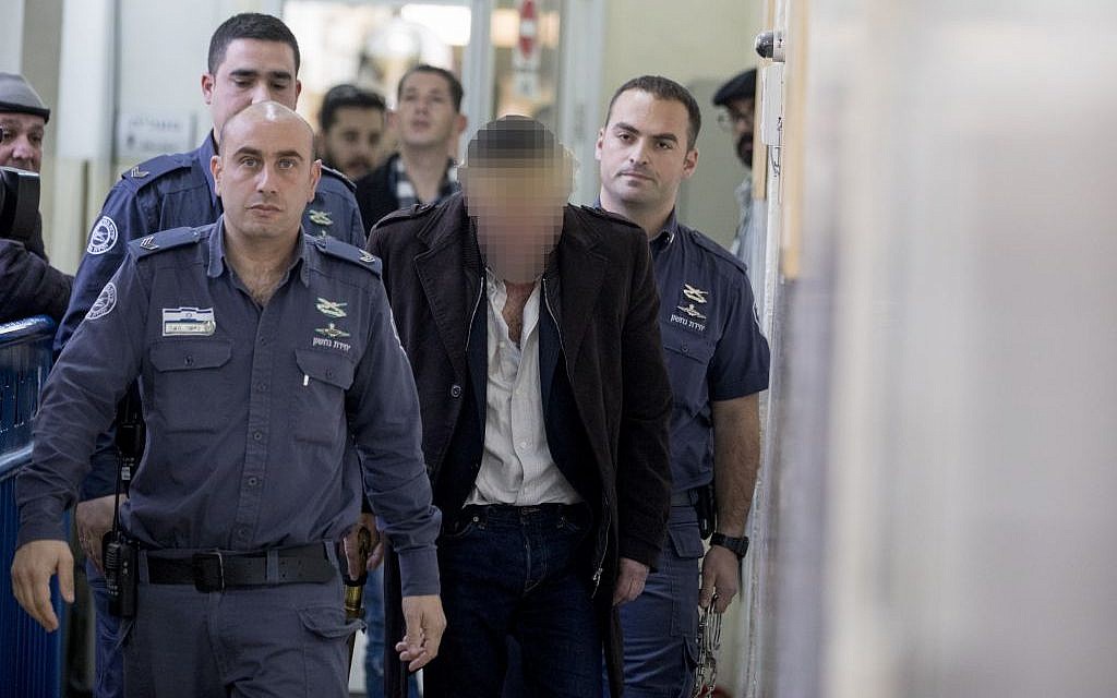 A 54-year-old man accused of threatening judges who convicted Elor Azaria is escorted by prison guards into the courtroom in the Magistrate’s Court in Jerusalem on January 5, 2017. (Yonatan Sindel/Flash90)