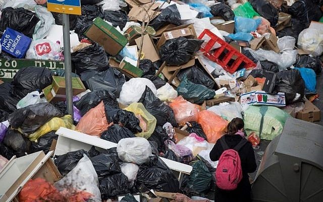 People walk past piles of garbage caused by a strike of the Jerusalem municipality, in Central Jerusalem, on January 31, 2017. (Yonatan Sindel/Flash90)