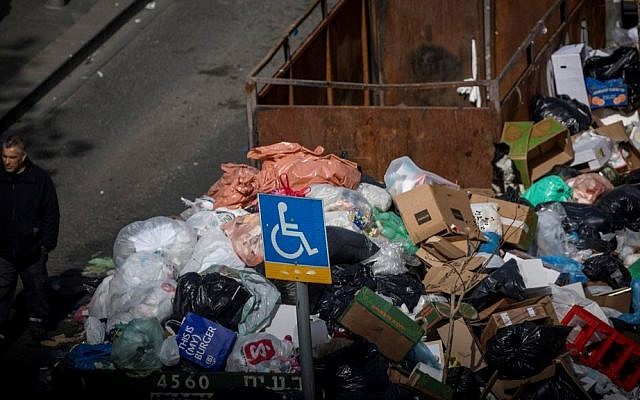 People walk past piles of garbage caused by a strike of the Jerusalem municipality, in Central Jerusalem, on January 31, 2017. (Yonatan Sindel/Flash90)