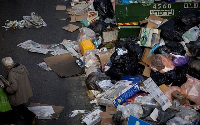 People walk past piles of garbage caused by a strike of the Jerusalem municipality, in Central Jerusalem, on January 31, 2017. (Yonatan Sindel/Flash90)