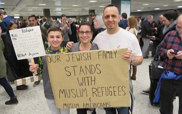 Jacob, left, Miri and Tal Zlotnitsky holding up a poster welcoming Muslim arrivals at Dulles International Airport in Virginia, Jan. 28 2017. (Ron Kampeas / JTA)