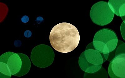 In this Thursday, Dec. 24, 2015, file photo, a nearly-full moon is seen among Christmas lights at a holiday display near Lenexa, Kan. (AP/Charlie Riedel, File)